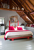 Double bed with picture frames below wooden ceiling in French farmhouse