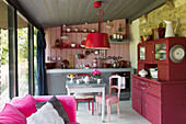 Red pendant shade above table in kitchen with painted dresser in Brittany cottage, France