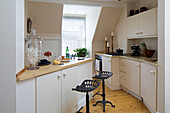 Black bar stools in angular cream fitted kitchen in Twickenham townhouse, Middlesex, England, UK