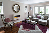 Circular mirror with corner sofa in pastel pink living room of London family home, England, UK