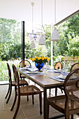 Cut roses on wooden dining table in Oxfordshire garden extension England UK