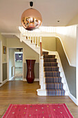 Striped staircase carpet with gold pendant light and large vase in Berkshire home, England, UK