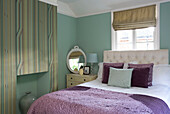 Purple bedspread with striped pain-effect chimney breast in Berkshire home, England, UK