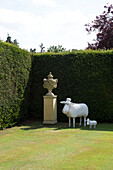 Contemporary sheep statues with historic plinth in corner of London garden, England, UK