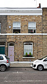 Cars parked in road at exterior of Georgian brick terraced house London England UK