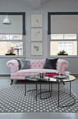 Pink Chesterfield sofa with nest of tables on rug at windows of Georgian London townhouse England UK