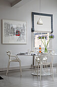 Modern artwork with dining table and chairs at window in London townhouse England UK