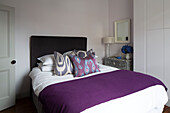 Purple blanket on double bed with built in storage in London townhouse England UK