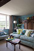 Assorted cushions on two seater sofa with wooden storage cupboard in Camber cottage East Sussex England UK