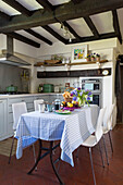 Weiße Stühle mit karierter Tischdecke in der Balkenküche von Camber cottage East Sussex England UK