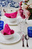 Bright pink napkins in bowls with cut flowers on table in London townhouse, England, UK