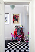 Childrens bikes and cycling helmets in hallway of London townhouse with black and white checked rug, England, UK
