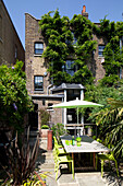 Parasol and table with chairs on terrace of brick four storey London townhouse, England, UK