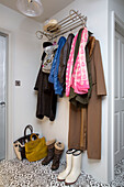 Coats and scarves with boots and bags on hallway shelf in London home, England, UK