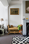 Hat on bench below gilt framed artwork in living room of London home, England, UK