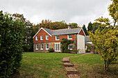 Detached Sussex farmhouse with brick path crossing lawn  UK