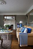 Gestreifte blaue Decke auf gelbem Sofa im Wohnzimmer mit Couchtisch in UK home