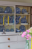 Blue and white crockery displayed in glass fronted dresser in UK home