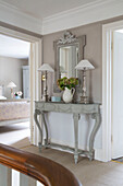 Pair of lamps with mirror on hallway console in UK home