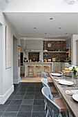 Open plan dining room with view to kitchen with exposed brick wall in Shoreham by Sea home   West Susses   England   UK