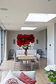 Großes rotes Blumenkunstwerk im offenen Esszimmer eines Hauses in Großbritannien