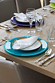Turquoise and purple place settings on wooden dining table in UK home