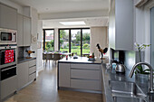 Open plan fitted kitchen and dining room with view through patio doors to garden of  UK home