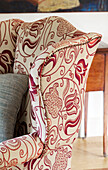 Red floral patterned armchair in Suffolk farmhouse living room,  England,  UK