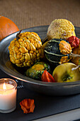 Assorted vegetables in metal bowl with lit candle in London home,  England,  UK