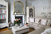Gilt framed mirror on mantlepiece with bookcases in cream Hertfordshire living room,  England,  UK