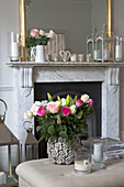 Cut roses with glass candle holders and marble fireplace in Hertfordshire living room,  England,  UK