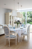Karierte Esszimmerstühle um den Tisch mit weißen Hängelampen in einem Haus in Hertfordshire, England, UK
