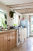 Wooden cupboard unit with light blue fridge in sunlit farmhouse kitchen,  Berkshire,  England,  UK