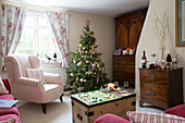 Gestreifter Sessel am Fenster des Wohnzimmers in Berkshire mit Weihnachtsbaum und Brettspiel, England, UK