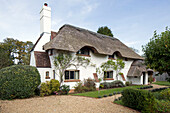 Gravel driveway in front garden of detached Sussex thatched cottage   England   UK
