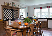 Wooden chairs at kitchen table with black and white tiled splashback above range oven in London home,  England,  UK