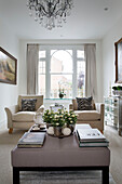 pair of armchairs and ottoman in living room with arched window in contemporary London home   UK