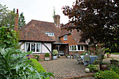 Dog stands on brick patio at front entrance of detached timber-framed and brick house   United Kingdom