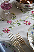 Silver forks on embroidered tablecloth in UK farmhouse
