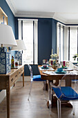 Pair of oriental lamps with dining table and Ghost chairs in blue dining room with Venetian blinds,  London,  England,  UK