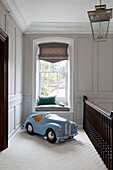 Large light blue toy car and window seat in hallway landing of Surrey home,  England,  UK