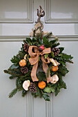 Pine cones and dried fruit in Christmas wreath on front door of Sussex home  England  UK