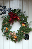 Dried oranges and pinecones in Christmas wreath with red ribbon on Lymington front door  Hampshire  UK