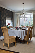 Glass chandelier above dining table set for six at Christmas in Chobham home   Surrey   England   UK