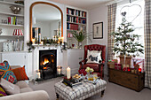 Roter Ledersessel und Weihnachtsbaum am beleuchteten Kamin im Wohnzimmer in Surrey England UK