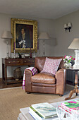 Brown leather sofa with gilt-framed oil painting in corner of Sussex living room   England   UK