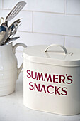 White metal 'SUMMER'S SNACKS' storage tin with utensils in kitchen of London townhouse   England   UK