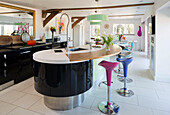Stools at curved breakfast bar in Sandhurst kitchen fitted with black units  Kent  England  UK