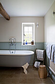 Freestanding bath at window in panelled East Dean farmhouse  West Sussex  UK
