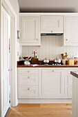 Saucepans on gas hob of white fitted kitchen in Surrey home, England, UK